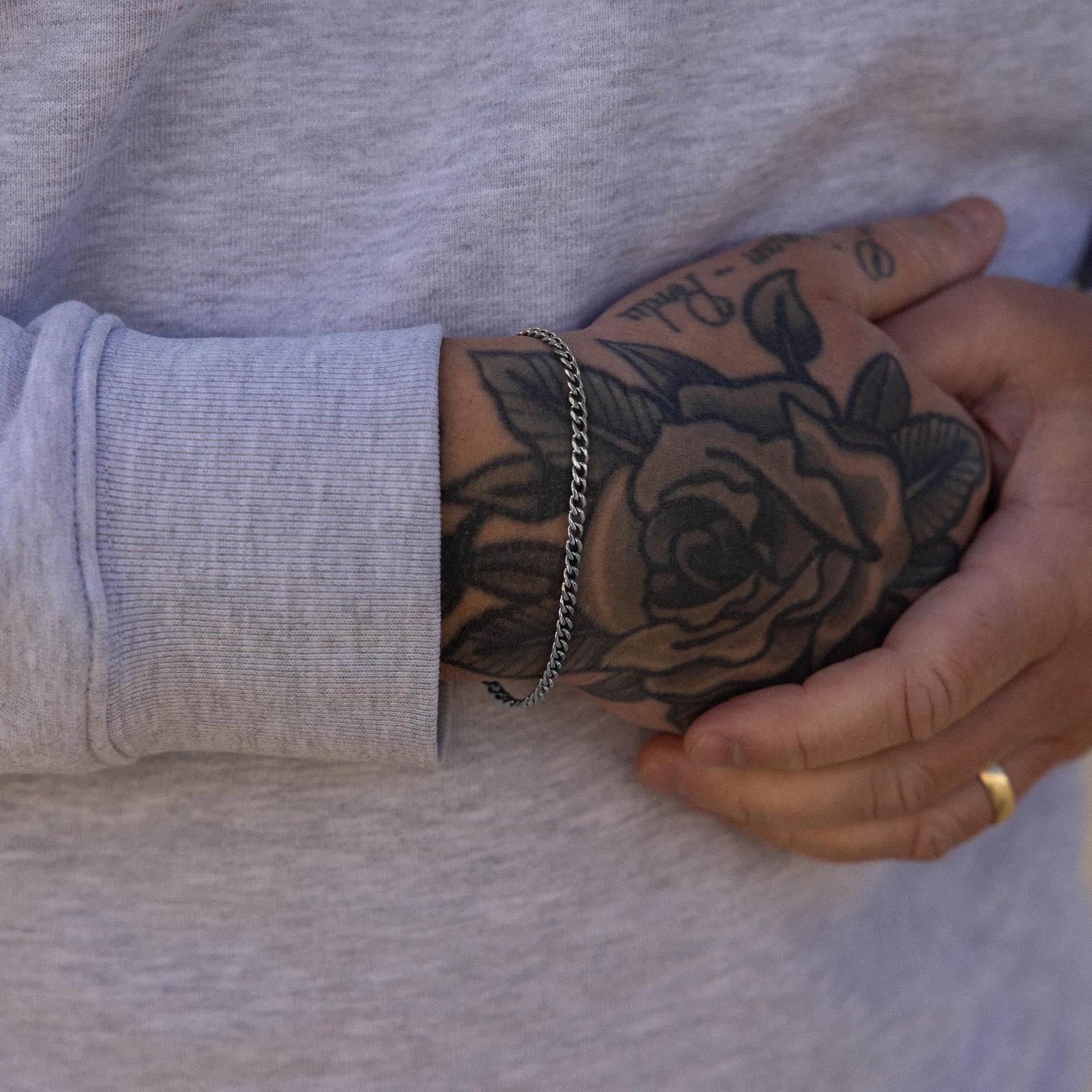 Silbernes Armband von PURELEI, getragen am Handgelenk mit Tattoo-Hintergrund.