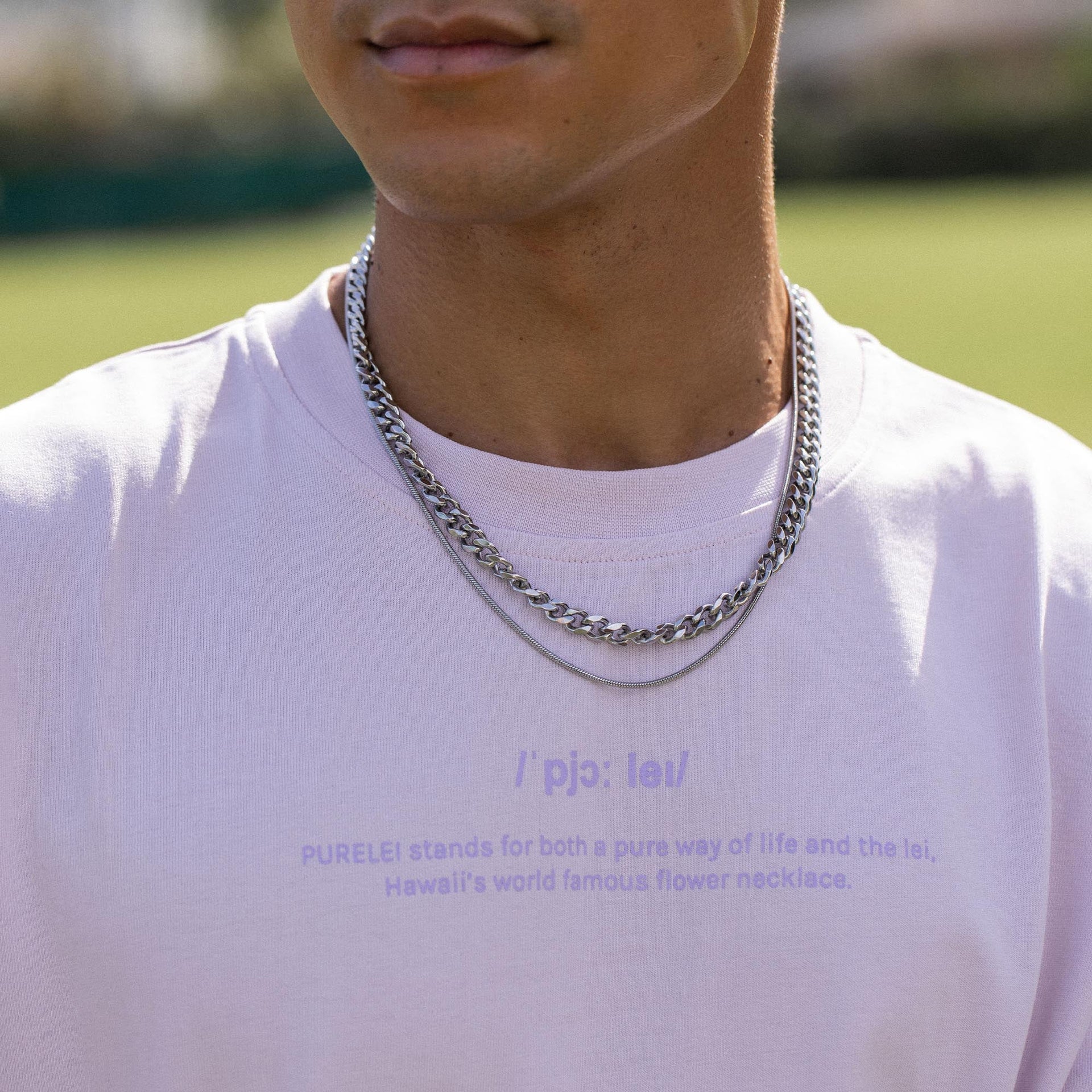 Silberne Kette mit glänzendem Finish, getragen über einem weißen T-Shirt, inspiriert von PURELEI.