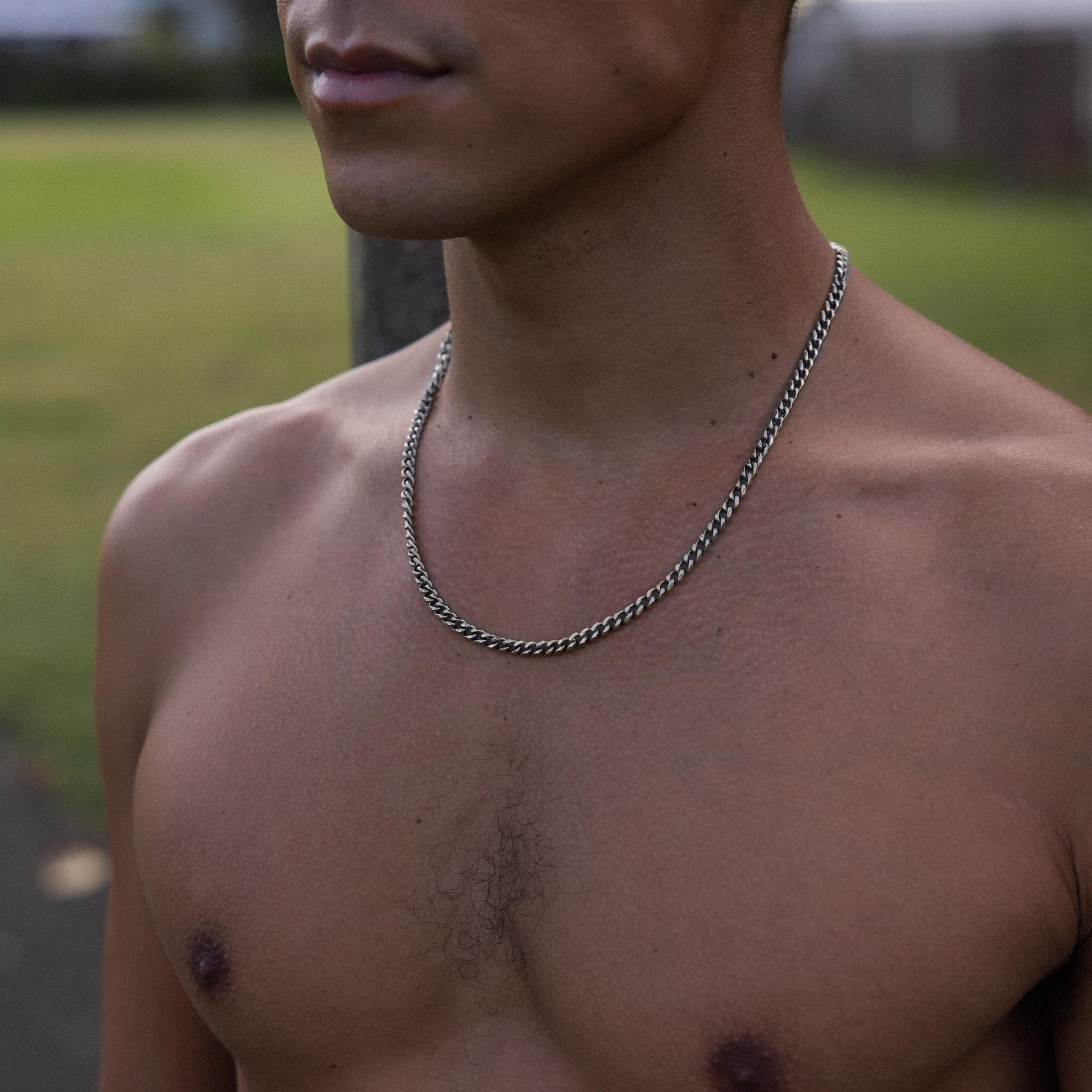 Silberne Kette mit geflochtenem Design, getragen von einem Mann im Freien, PURELEI.