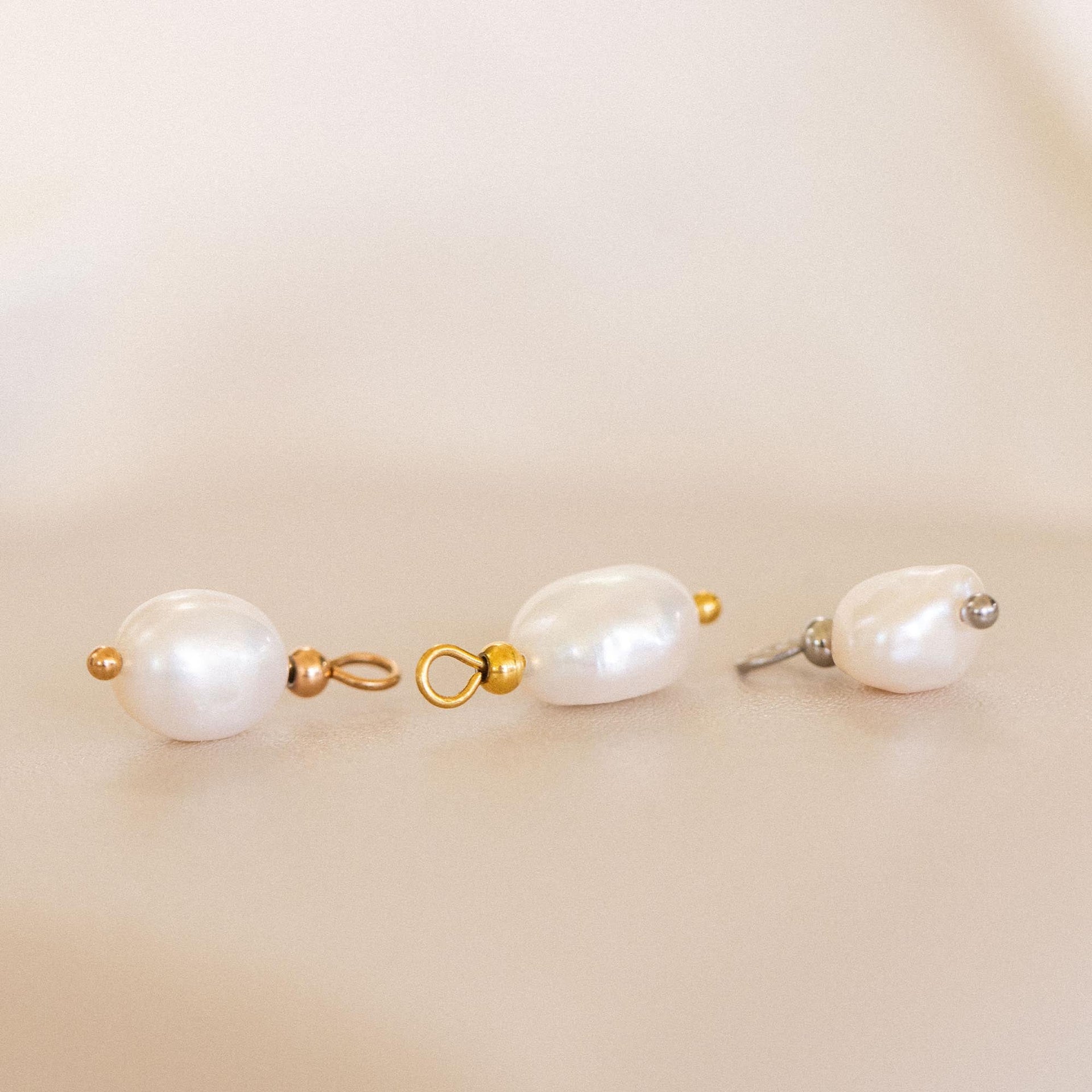 Schimmernder Keshi Perlen Charm in Gold, Silber und Roségold, edel inszeniert auf sanftem beigem Hintergrund – PURELEI.