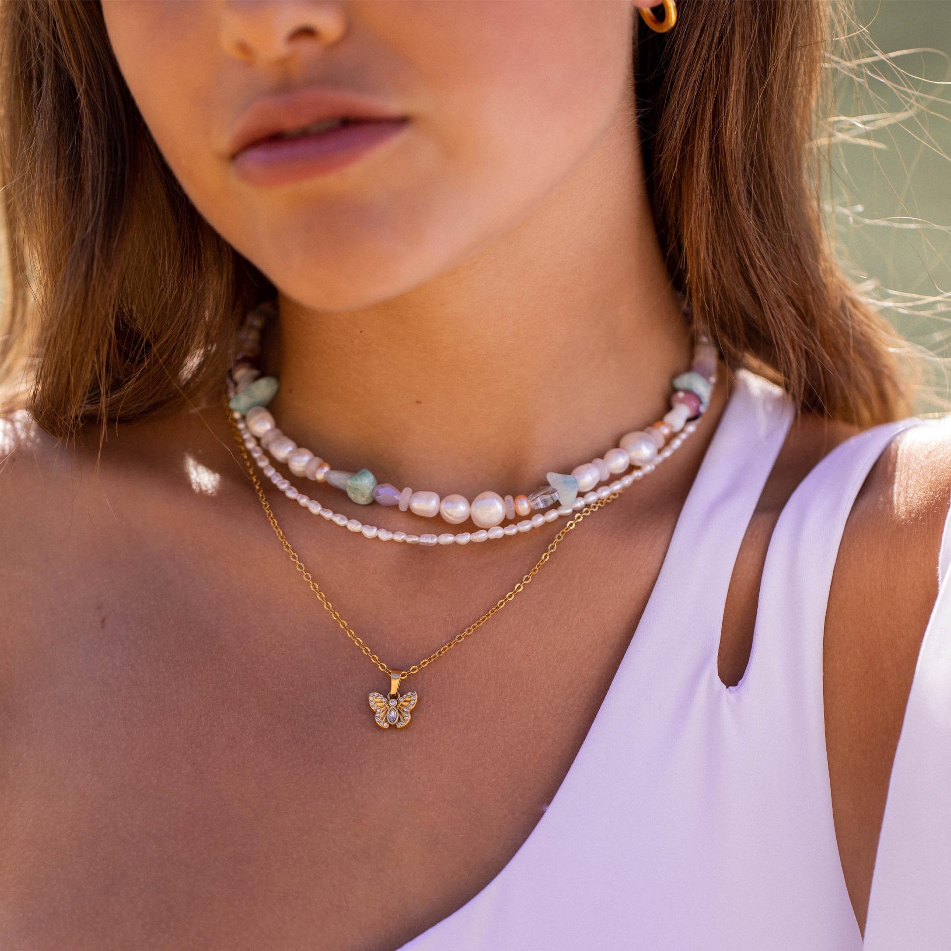 Dreifache Perlenkette mit goldener Schmetterlingsanhänger von PURELEI, elegant und feminin.