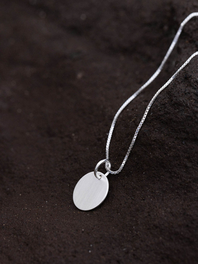 Perfection Charm von PURELEI: runder, nickelfreier Silberanhänger an filigraner Kette, puristisch und elegant inszeniert.