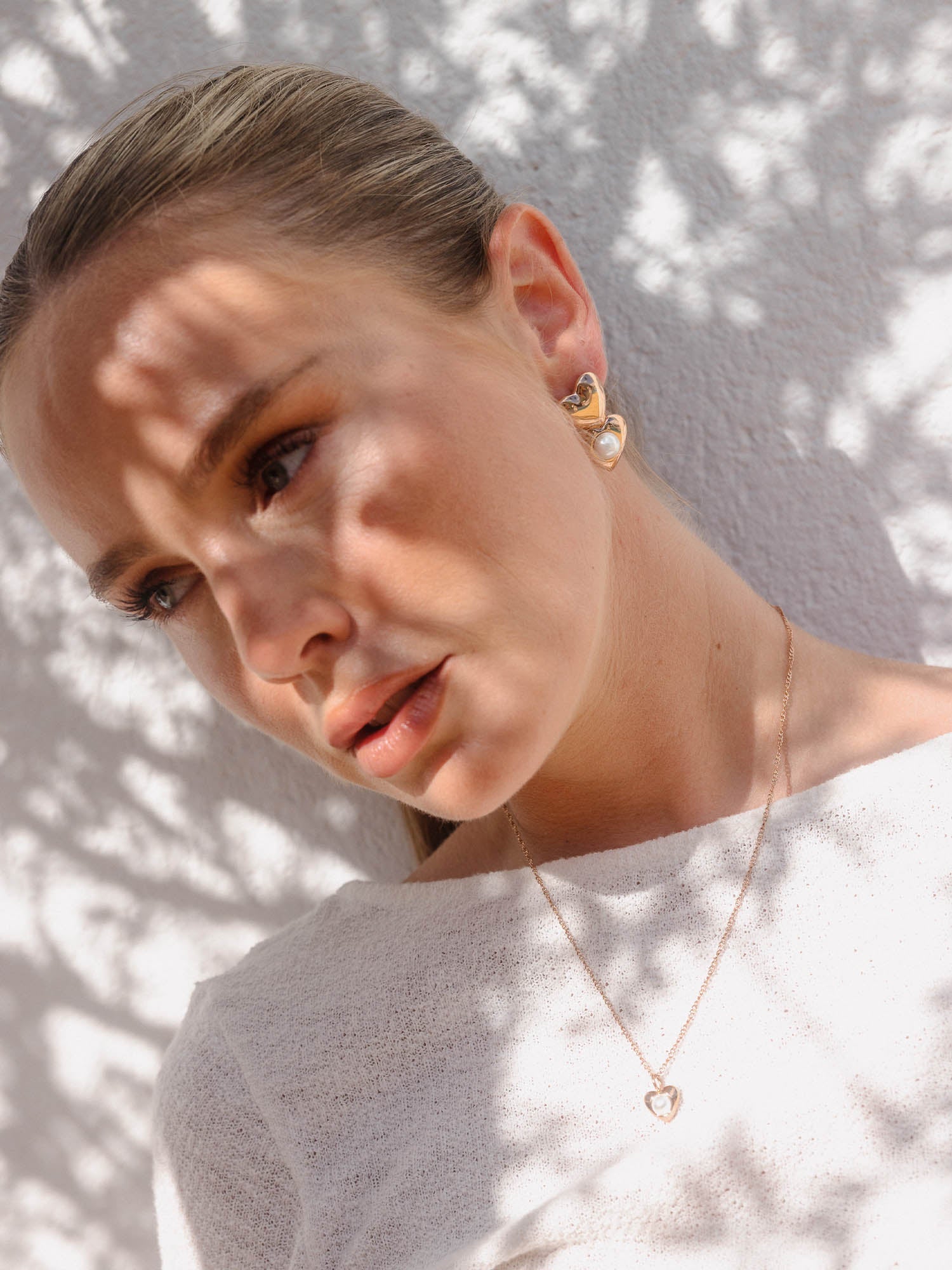 Roségoldene Herz-Kette und Ohrringe von PURELEI, elegant mit sanften Lichtspielen.