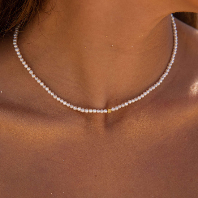 Zarte, rosafarbene Perlenkette von PURELEI, elegant am Hals getragen.