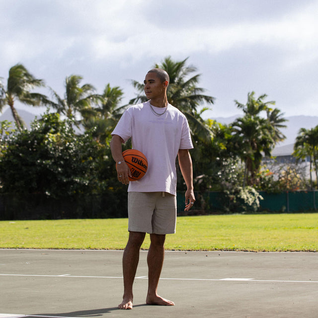 Mann in lässigem Outfit mit Basketball, umgeben von tropischer Natur – PURELEI Lifestyle.