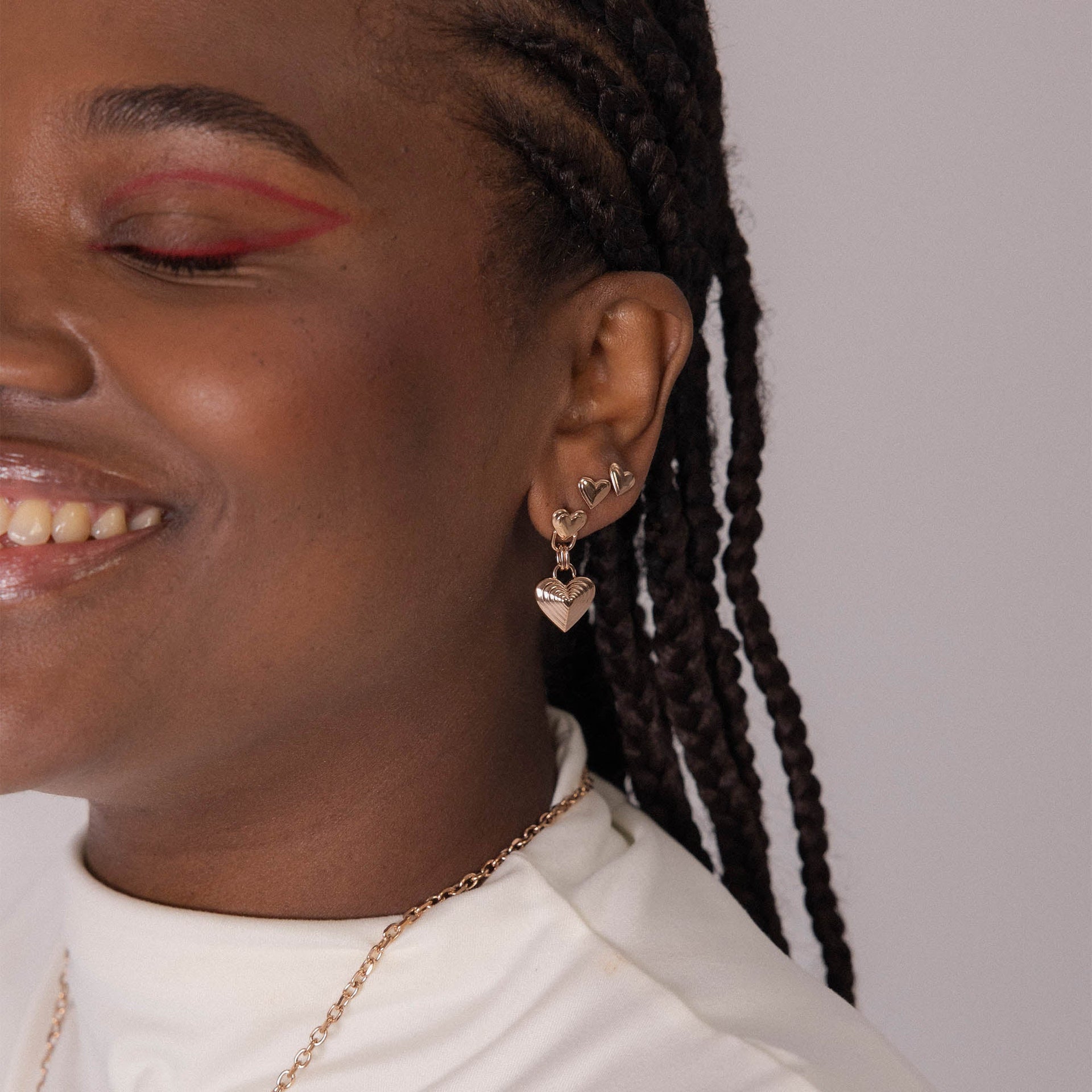 Silberne Herz-Ohrringe von PURELEI, elegant und verspielt, getragen mit einem Lächeln.