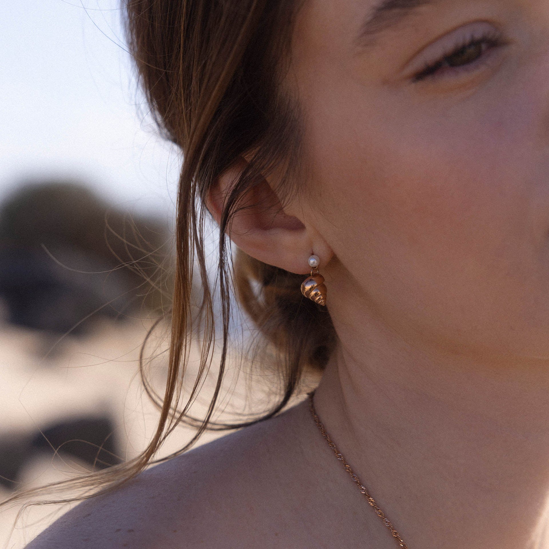 Roségoldene Muschel-Ohrringe mit Perle, getragen in sonniger Strandatmosphäre – PURELEI.
