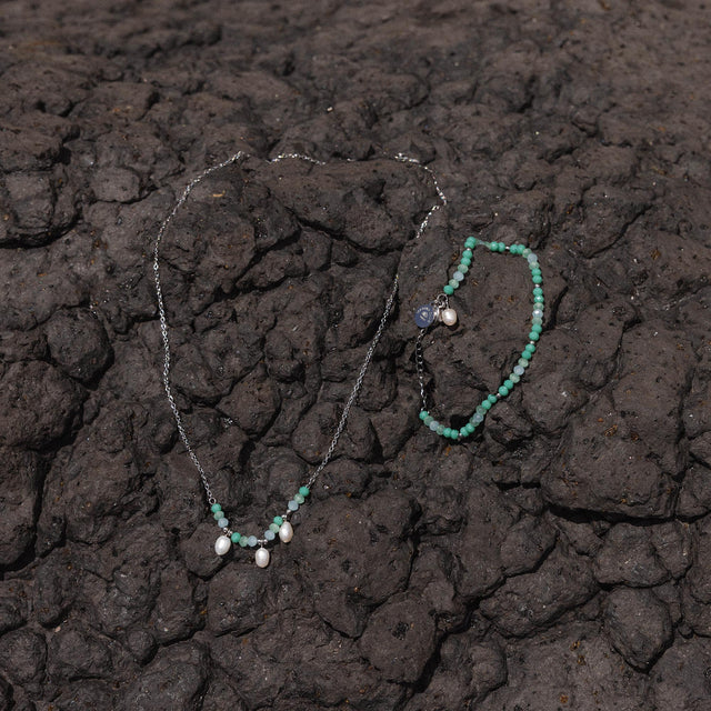 Silberne Kette und Armband mit runden Anhängern auf dunklem Lavagestein von PURELEI.