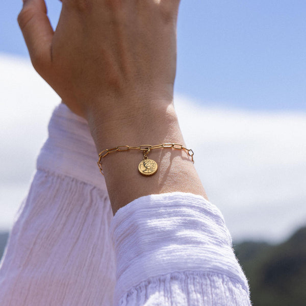 Goldenes Armband mit Anhänger, getragen im Sonnenlicht, von PURELEI.