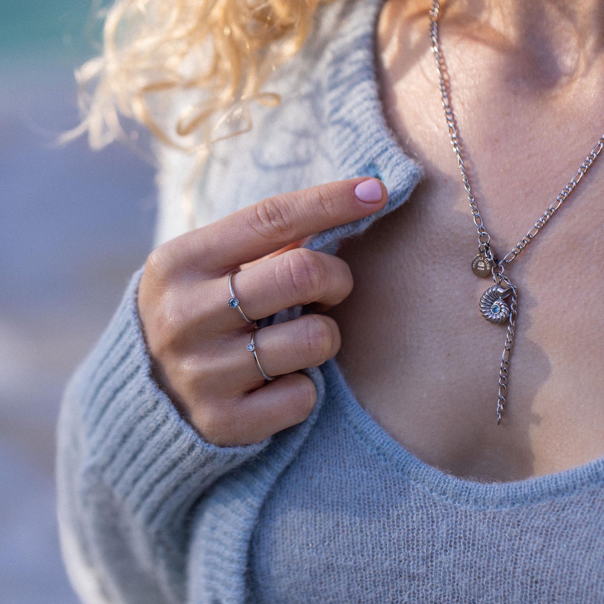 Silberne Kette mit Muschel-Anhänger, getragen mit grauem Pullover, PURELEI Stil.