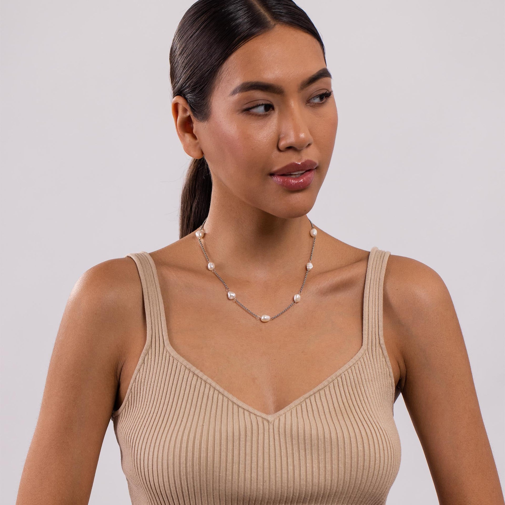 PURELEI Malahi Kette mit Süßwasserperlen und vergoldetem Edelstahl, elegant getragen in natürlichem Licht.