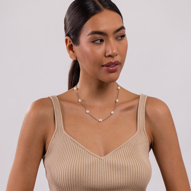 PURELEI Malahi Kette mit Süßwasserperlen und vergoldetem Edelstahl, elegant getragen in natürlichem Licht.