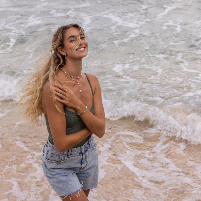 PURELEI Malahi Kette mit 18K Gold und Süßwasserperlen, getragen am Strand, strahlt elegante Sommerfrische aus.