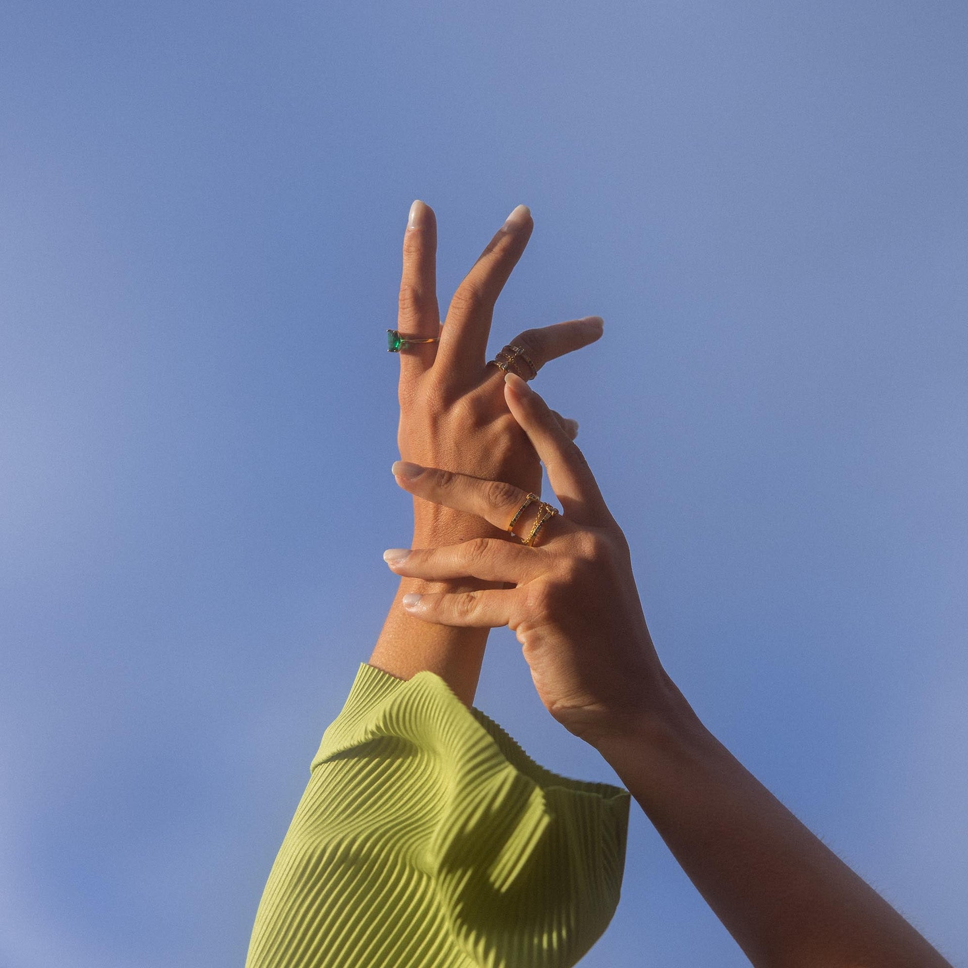 Hände mit goldenen Ringen vor blauem Himmel, PURELEI inspiriert.