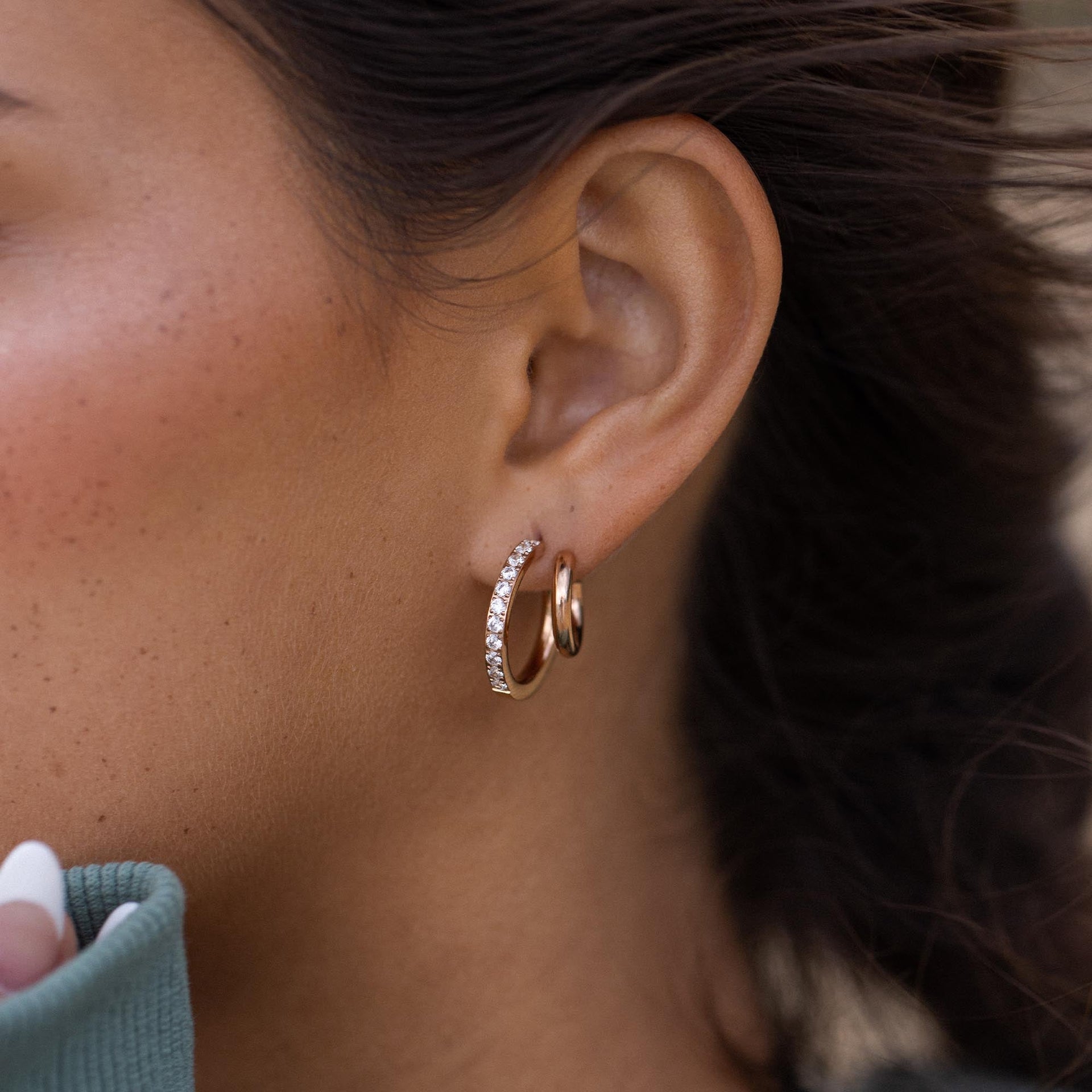 Roségoldene Creolen mit funkelnden Details, getragen von PURELEI, elegant und feminin.