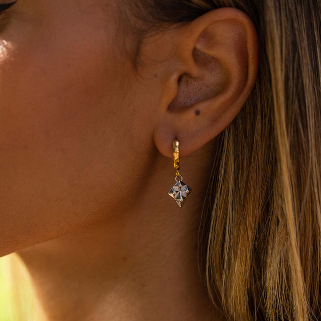 Goldene Ohrringe mit geometrischem Design, getragen in warmem Licht – PURELEI.