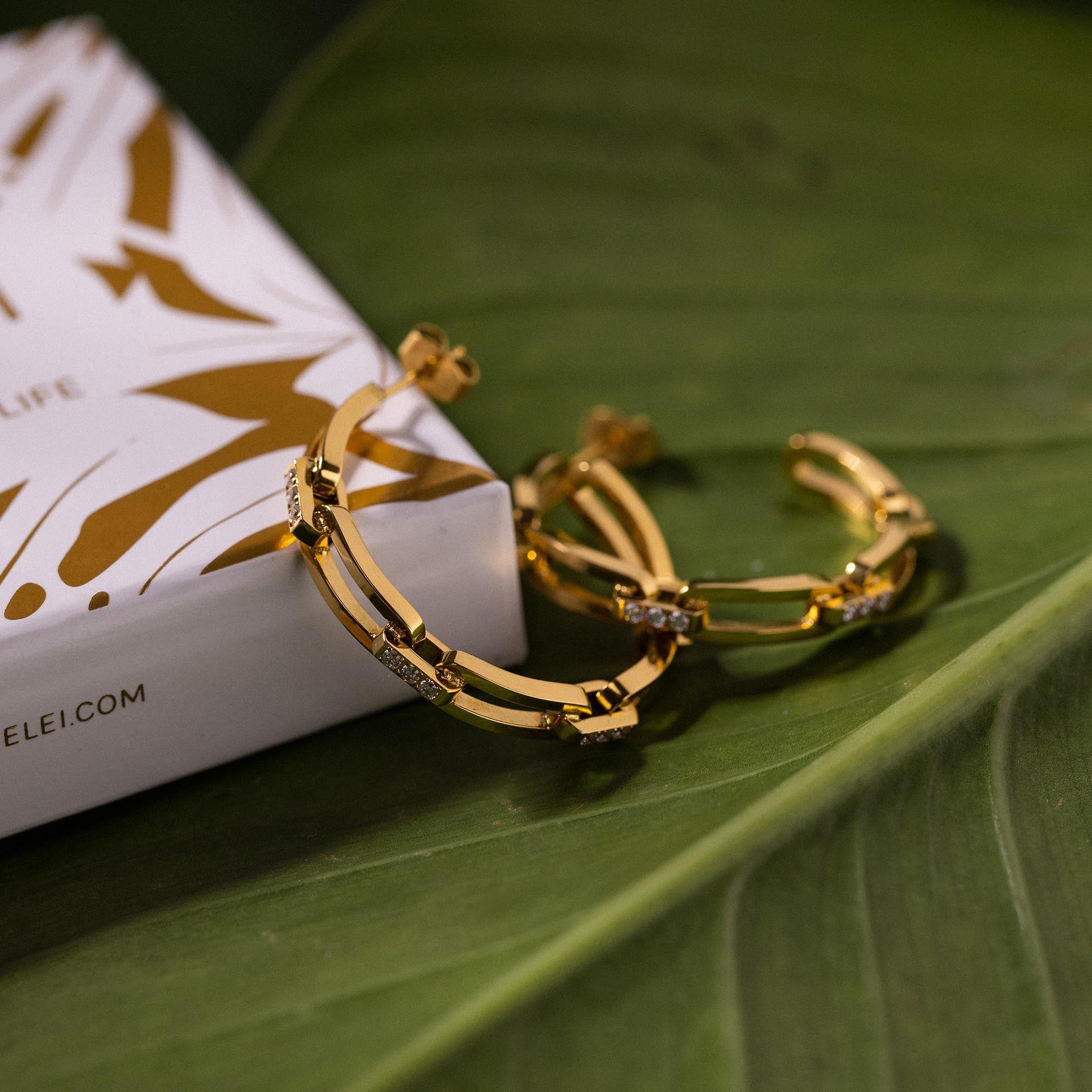 Always Ohrringe von PURELEI, vergoldete Creolen im Ketten-Glieder-Look mit funkelnden Zirkonia auf grünem Blatt.