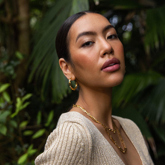 PURELEI Always Ohrringe, goldene Creolen im Ketten-Glieder-Look mit Zirkonia, elegant und feminin vor tropischem Grün.