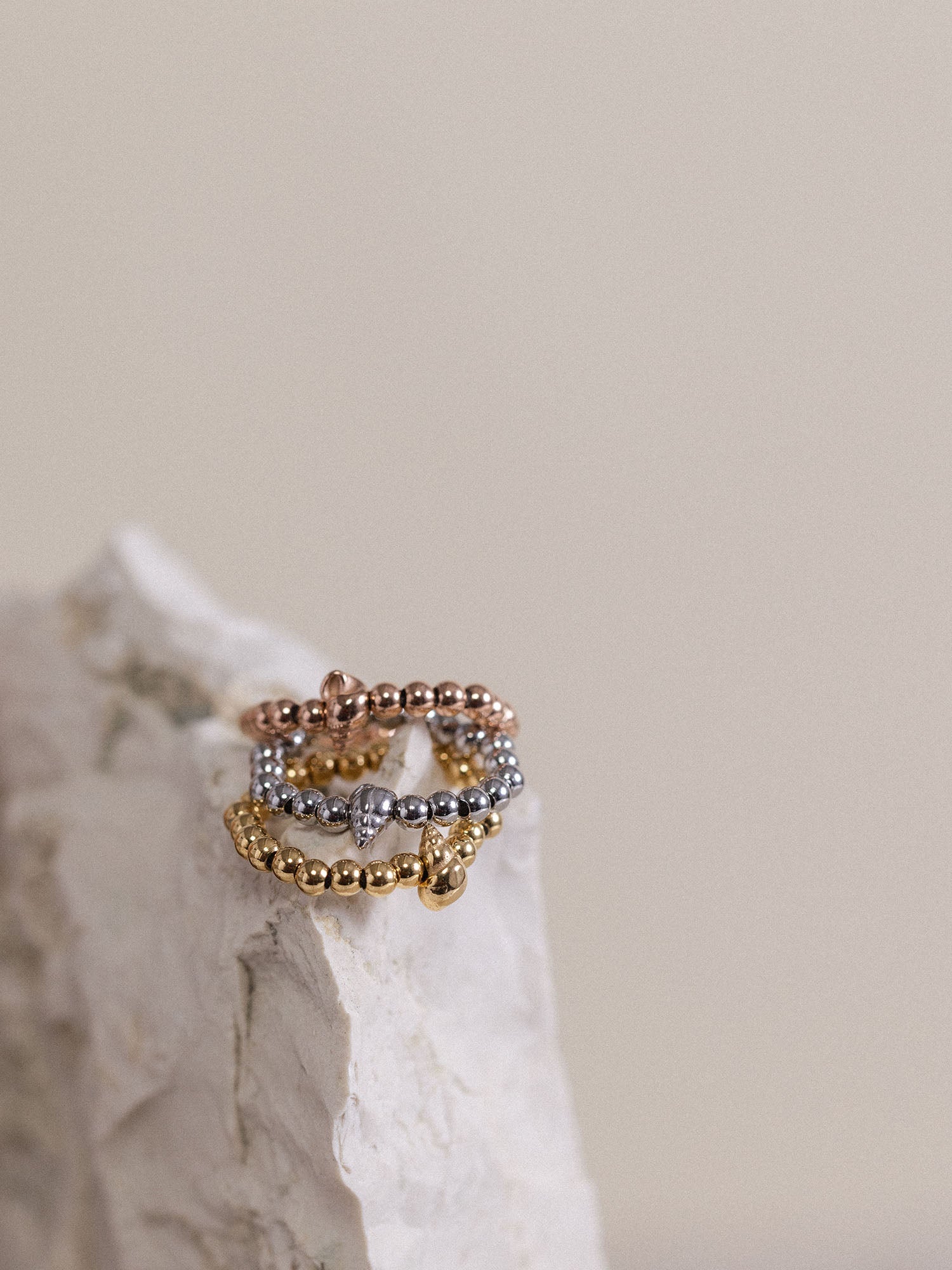 Oceanside Ring von PURELEI in Gold, Silber und Roségold mit Muschel-Detail, elegant auf hellem Stein arrangiert.