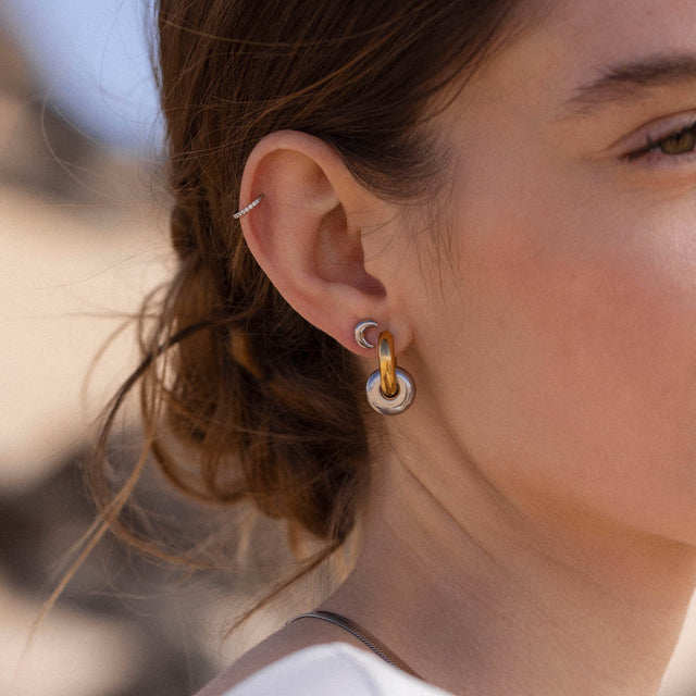 Roségoldene Creolen und Ohrstecker von PURELEI, elegant und modern, getragen in natürlicher Umgebung.