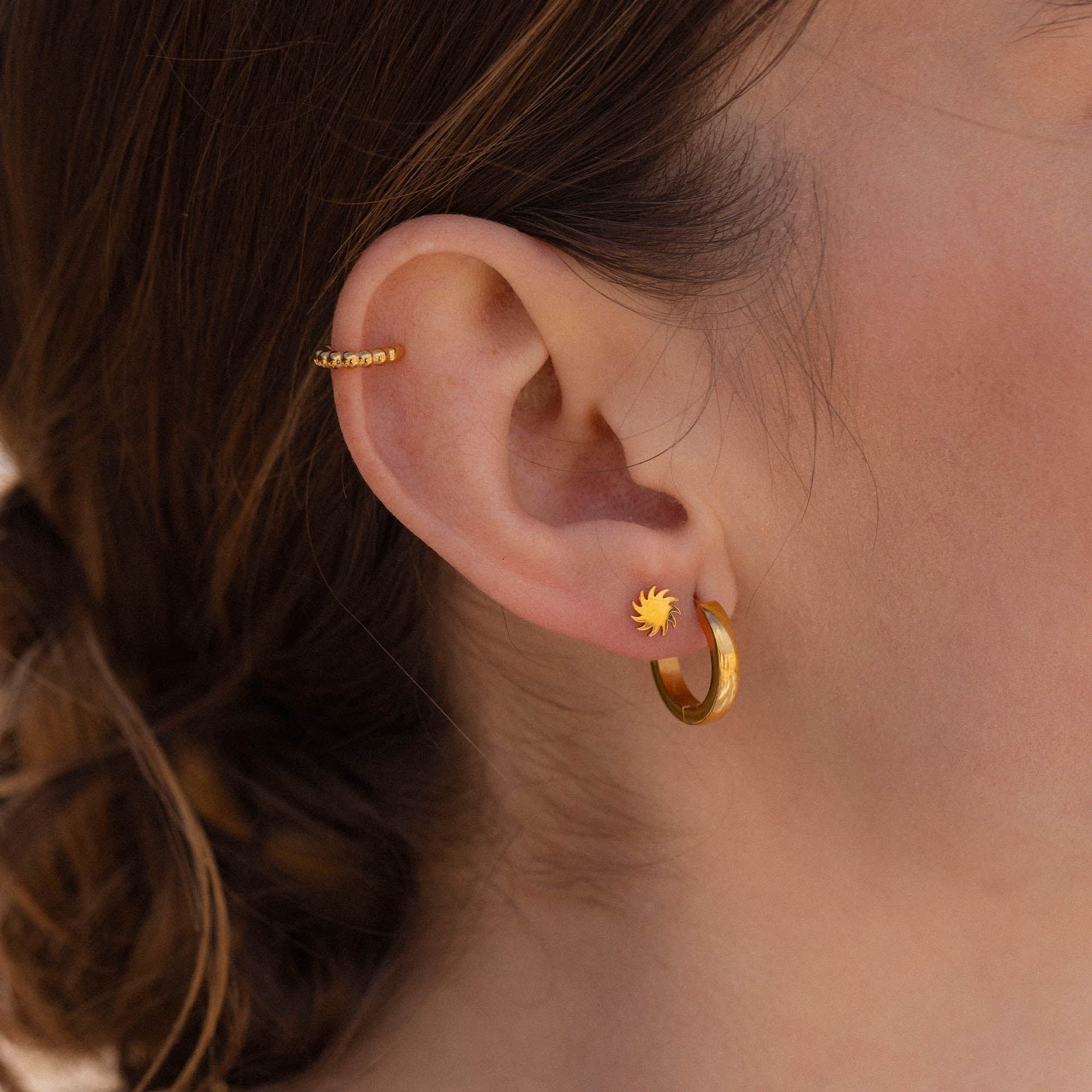Goldene Creolen und Ohrstecker mit Sonnenmotiv von PURELEI, elegant und feminin.