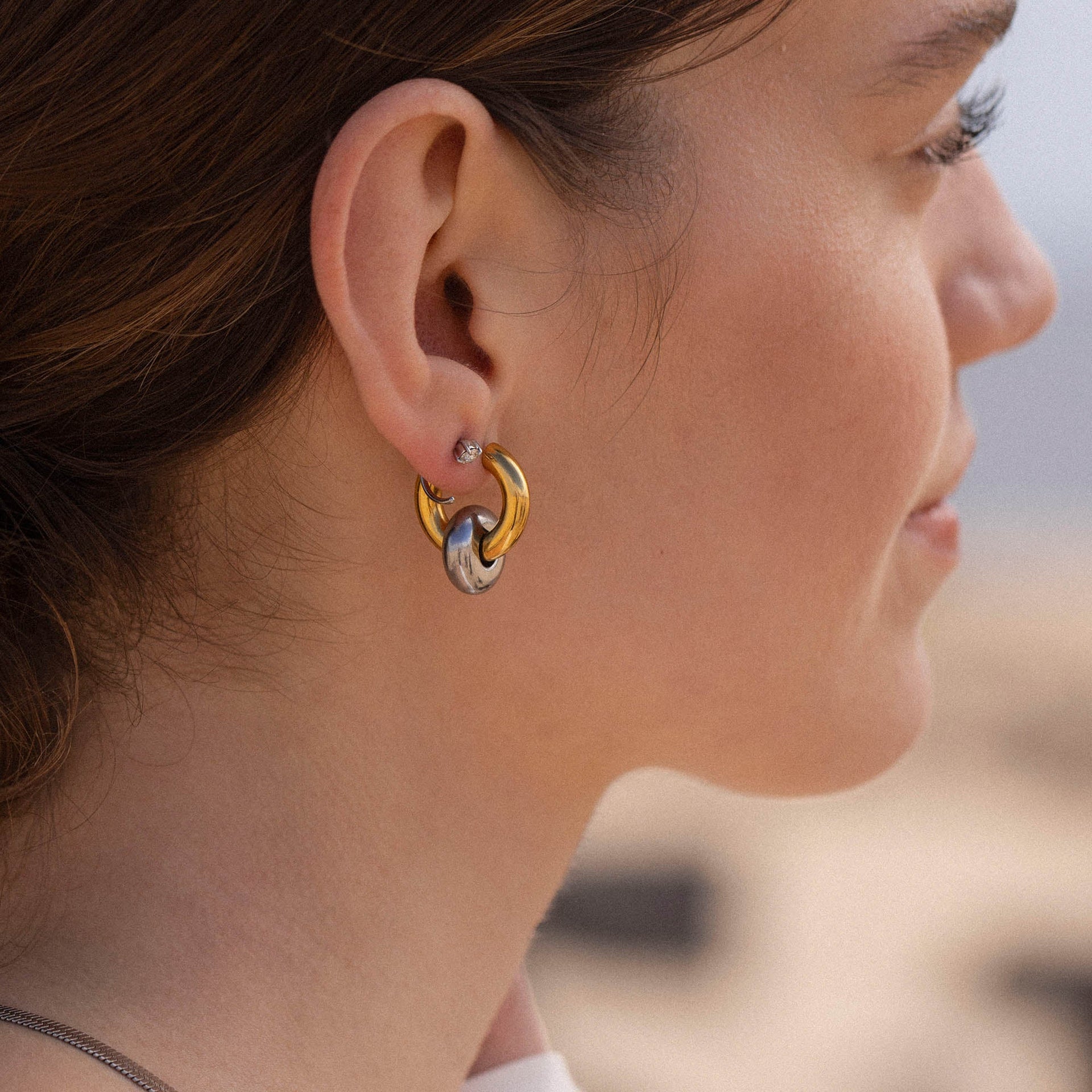 Silberne Creolen mit Wellenstruktur, getragen von einer Frau, PURELEI inspiriert.