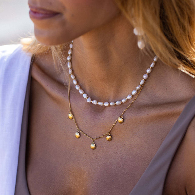 Zarte PURELEI Perlenkette und goldene Muschel-Anhänger, elegant und feminin.