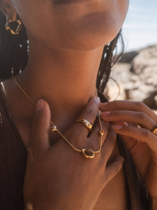 Roségoldene PURELEI Kette und Ringe, elegant und feminin, in warmem Licht getragen.