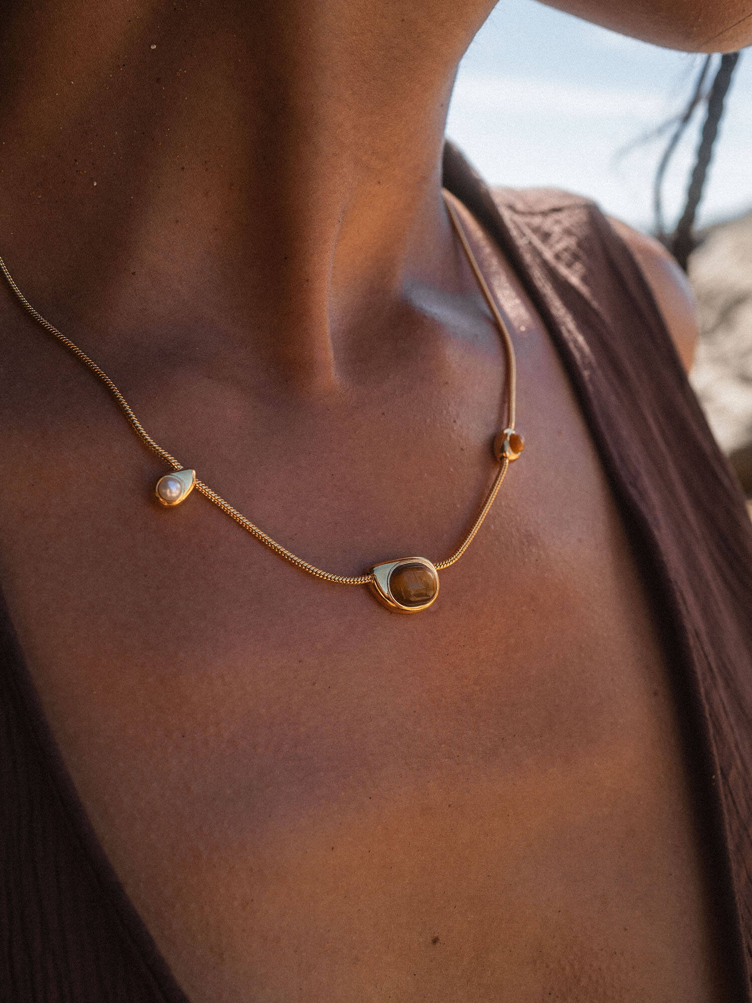 Elegante PURELEI Kette aus Roségold mit Muschelanhänger, getragen auf bronzefarbenem Hautton.