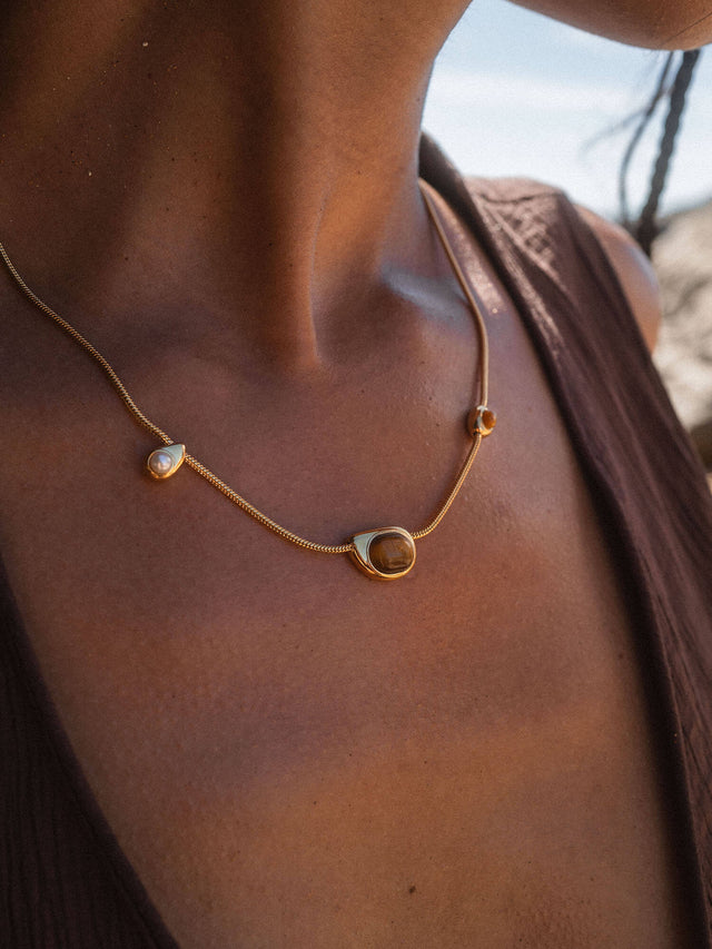 Elegante PURELEI Kette aus Roségold mit Muschelanhänger, getragen auf bronzefarbenem Hautton.