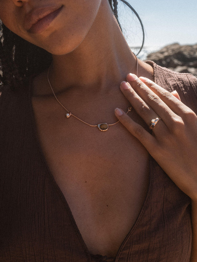 Goldene PURELEI Kette mit einzigartigem Design, getragen in warmem Licht.