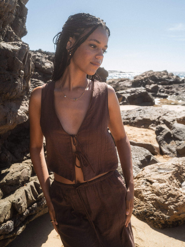 Braunes, lässiges Outfit am Strand, inspiriert von PURELEI, umgeben von Felsen.