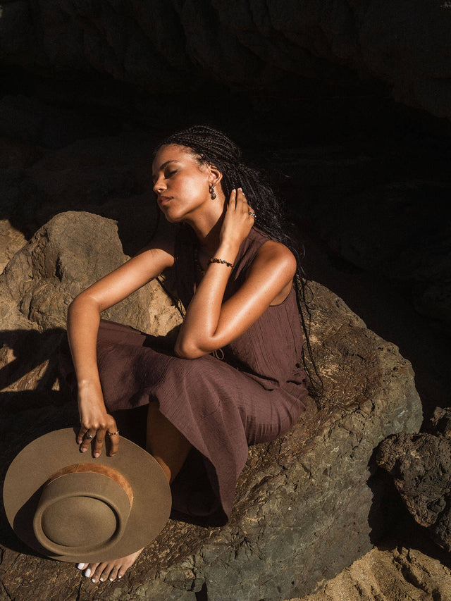 Tiger's Eye Armband von PURELEI aus goldbraunen Edelsteinperlen, getragen in natürlicher, sonnenverwöhnter Felsenlandschaft