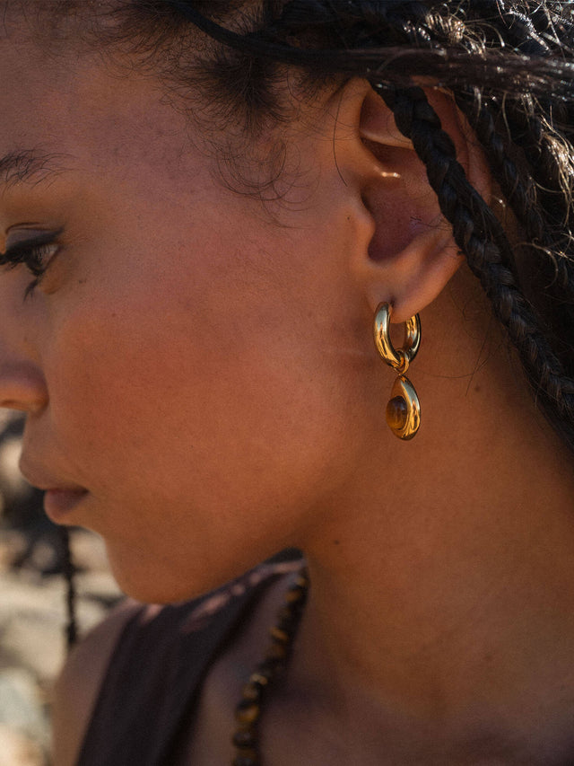 Goldene Creolen mit elegantem Design, getragen von einer Frau, PURELEI.