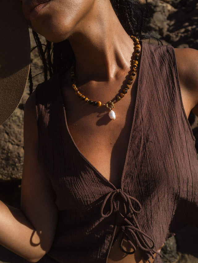 Braune PURELEI Halskette mit Muschel-Anhänger, getragen in warmem Licht.