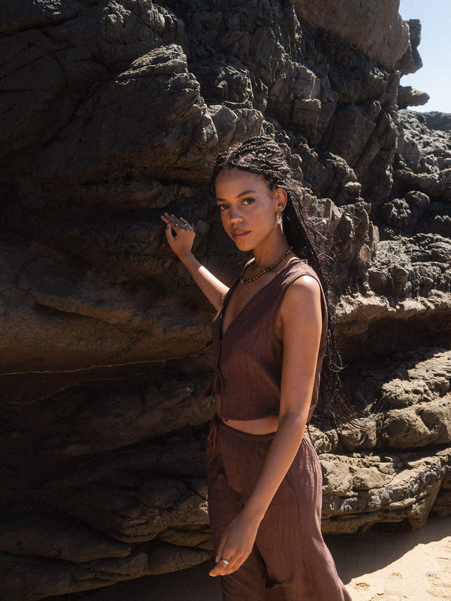 Braunes, leichtes Outfit vor rauem Felsen, inspiriert von PURELEI's Aloha-Feeling.