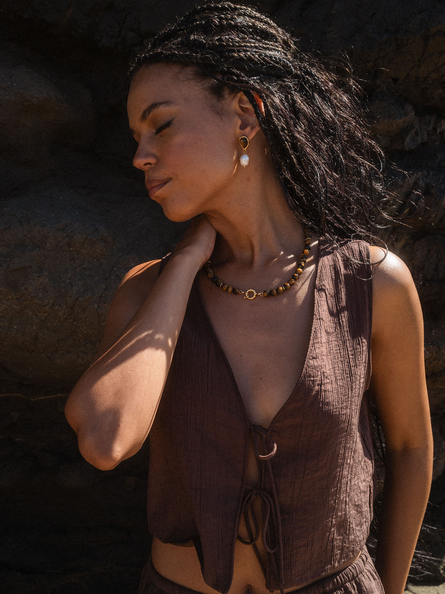 Braune, natürliche Schmuckstücke von PURELEI, getragen in tropischer Atmosphäre.