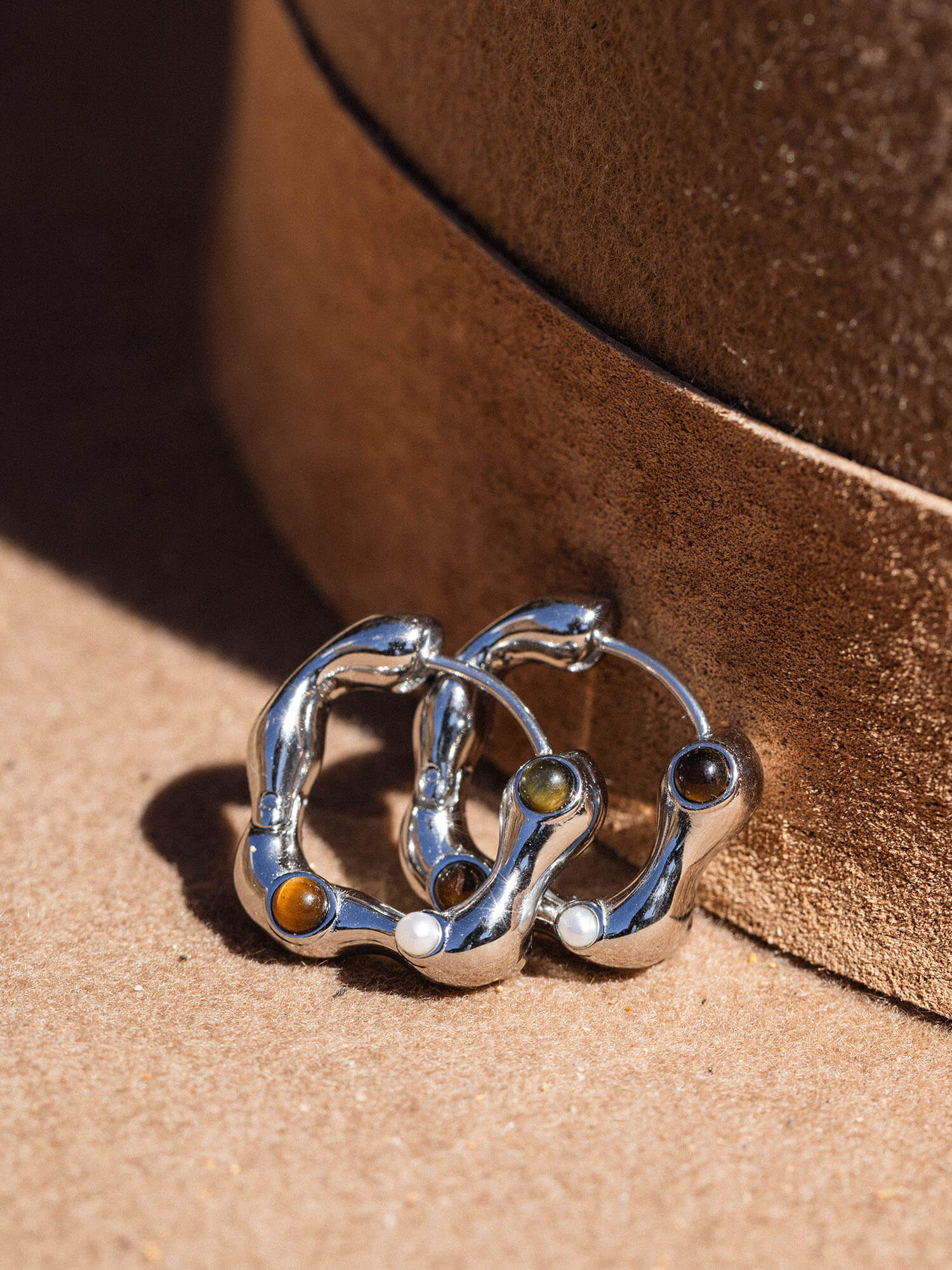 Silberne Creolen mit braunen Akzenten auf braunem Untergrund von PURELEI.