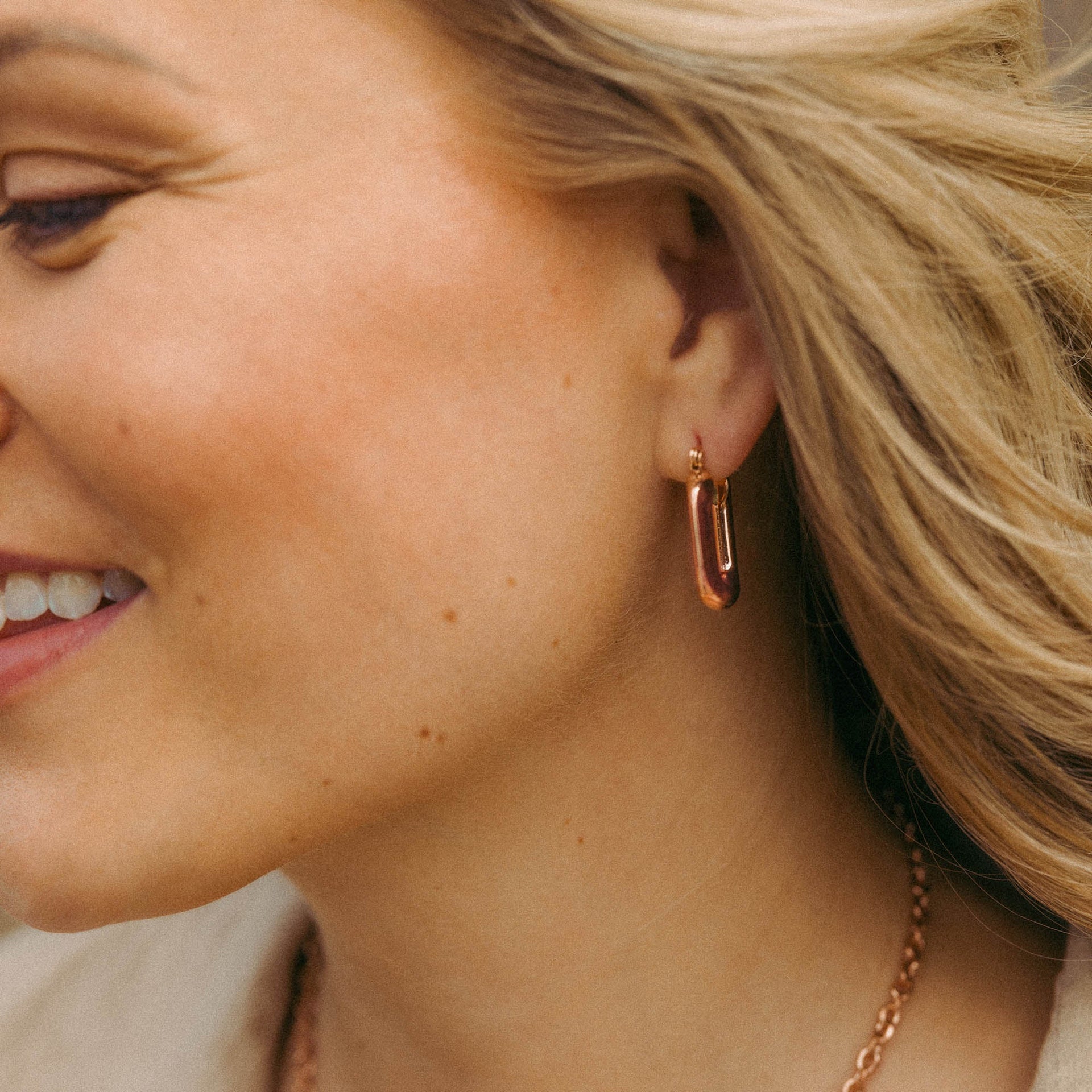 Roségoldene Ohrringe mit modernem Design, getragen von einer Frau, PURELEI.