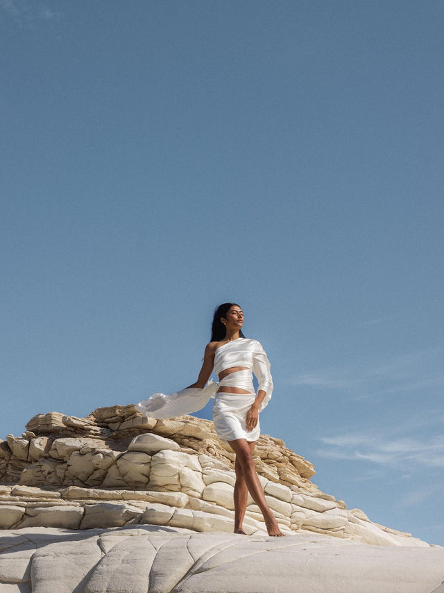 Taurus Letter Charm in 18K Gold, filigran, nickelfrei, elegant an heller Felslandschaft mit klarem Himmel getragen, PURELEI