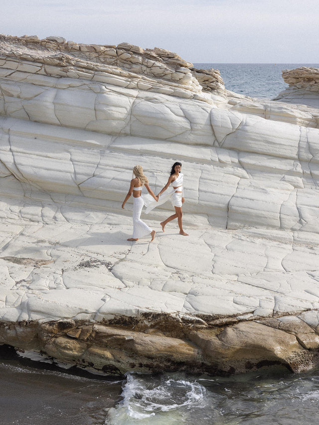 PURELEI Taurus Letter Charm aus vergoldetem Edelstahl, schlichtes Design vor natürlichem Küstenfelsen, zeitlose Eleganz