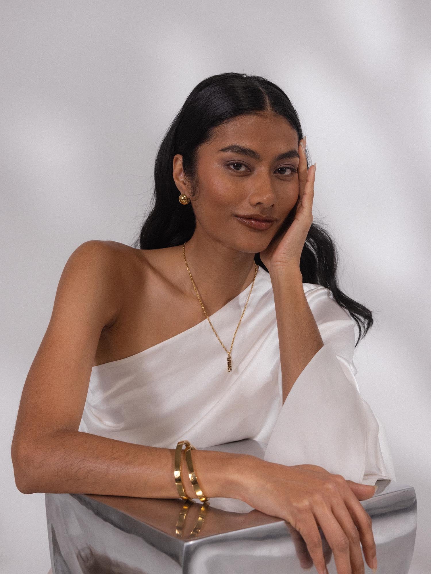 PURELEI Aries Letter Charm in vergoldetem Edelstahl, elegant und feminin getragen mit weißer Seidenbluse