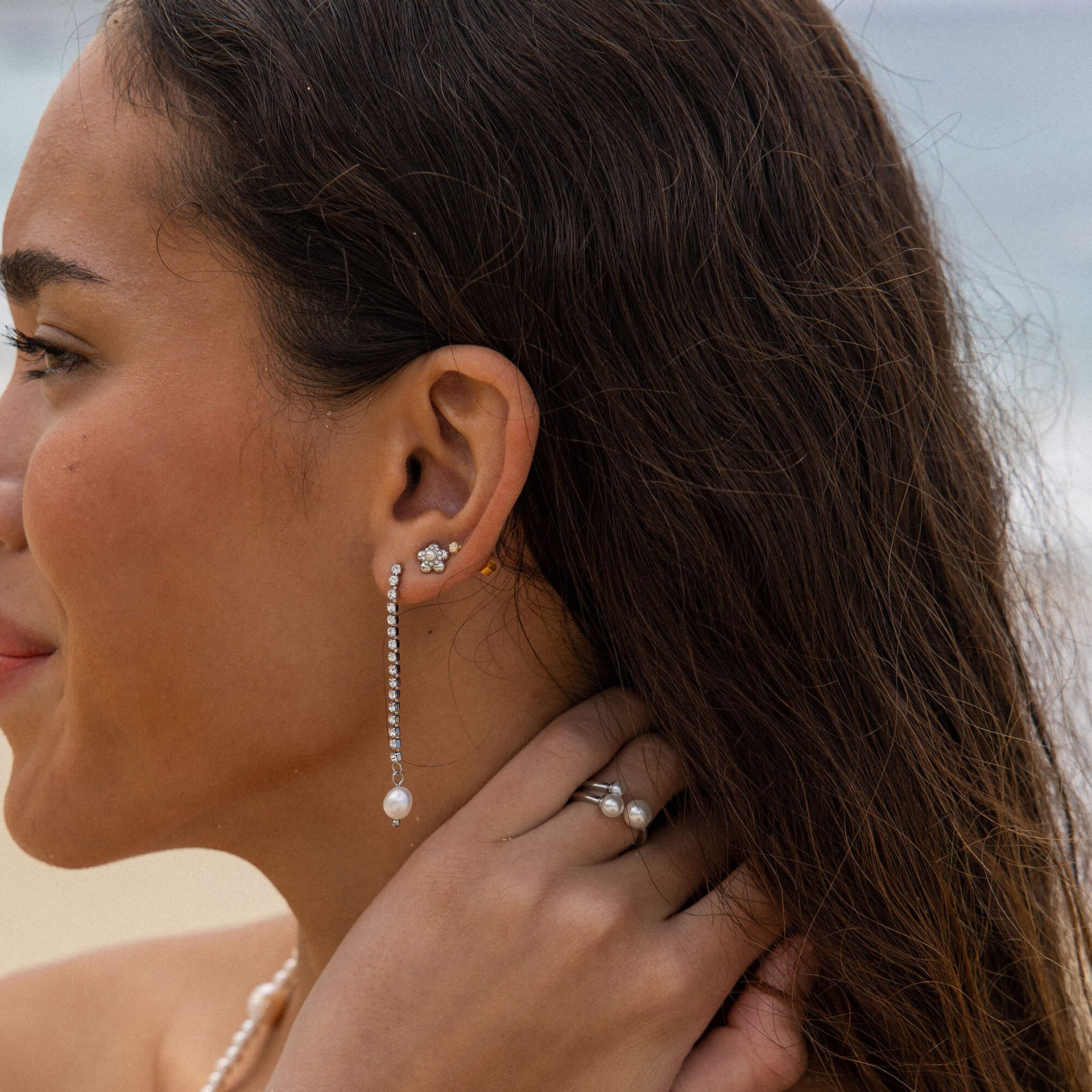 Silberne Ohrringe mit Perlen und Blumenmotiv, getragen von einer Frau, PURELEI.