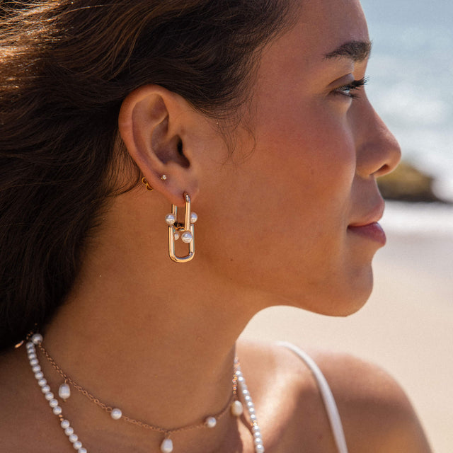 Roségoldene Ohrringe mit Perlen, getragen am Strand – PURELEI inspiriert.