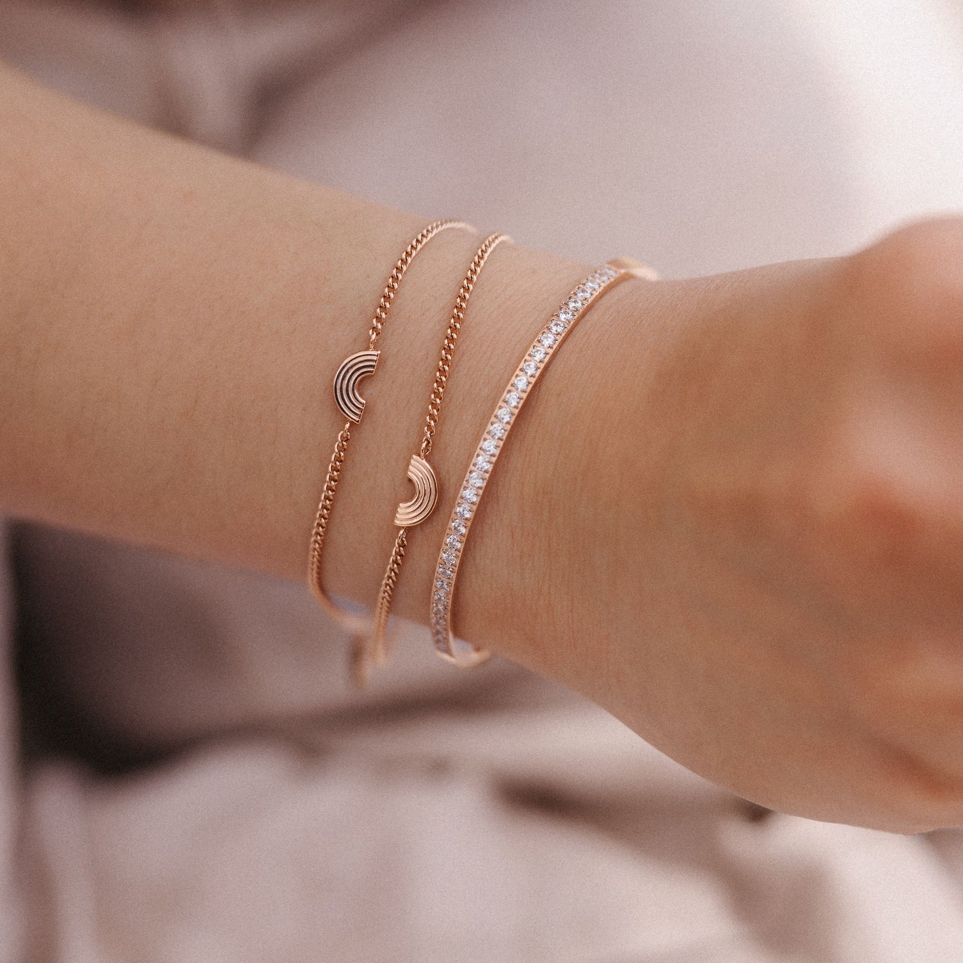 Drei roségoldene Armbänder mit funkelnden Details, getragen von PURELEI.