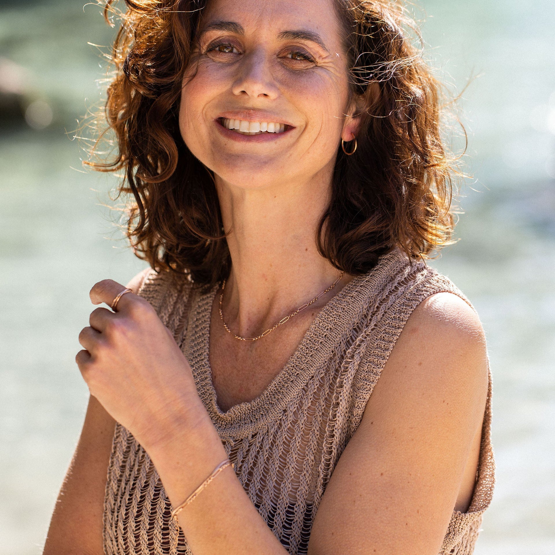 Zarte, goldene PURELEI Kette und Armband, getragen in sonniger, entspannter Atmosphäre.