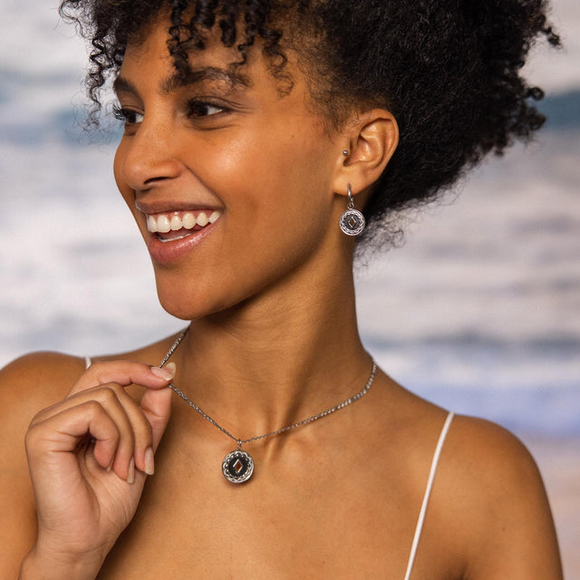 Silberne Kette und Ohrringe mit braunem Stein, getragen von einer lächelnden Frau, PURELEI.