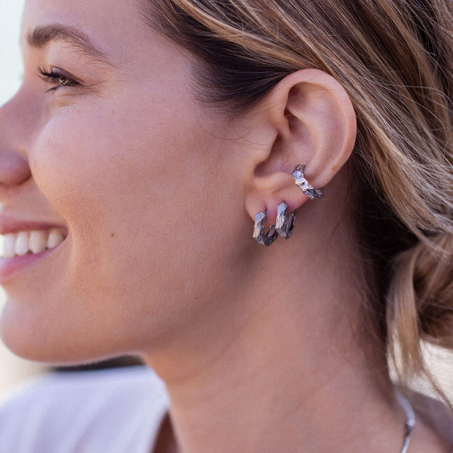 Silberne Creolen mit strukturiertem Design, getragen von einer lächelnden Frau, PURELEI.