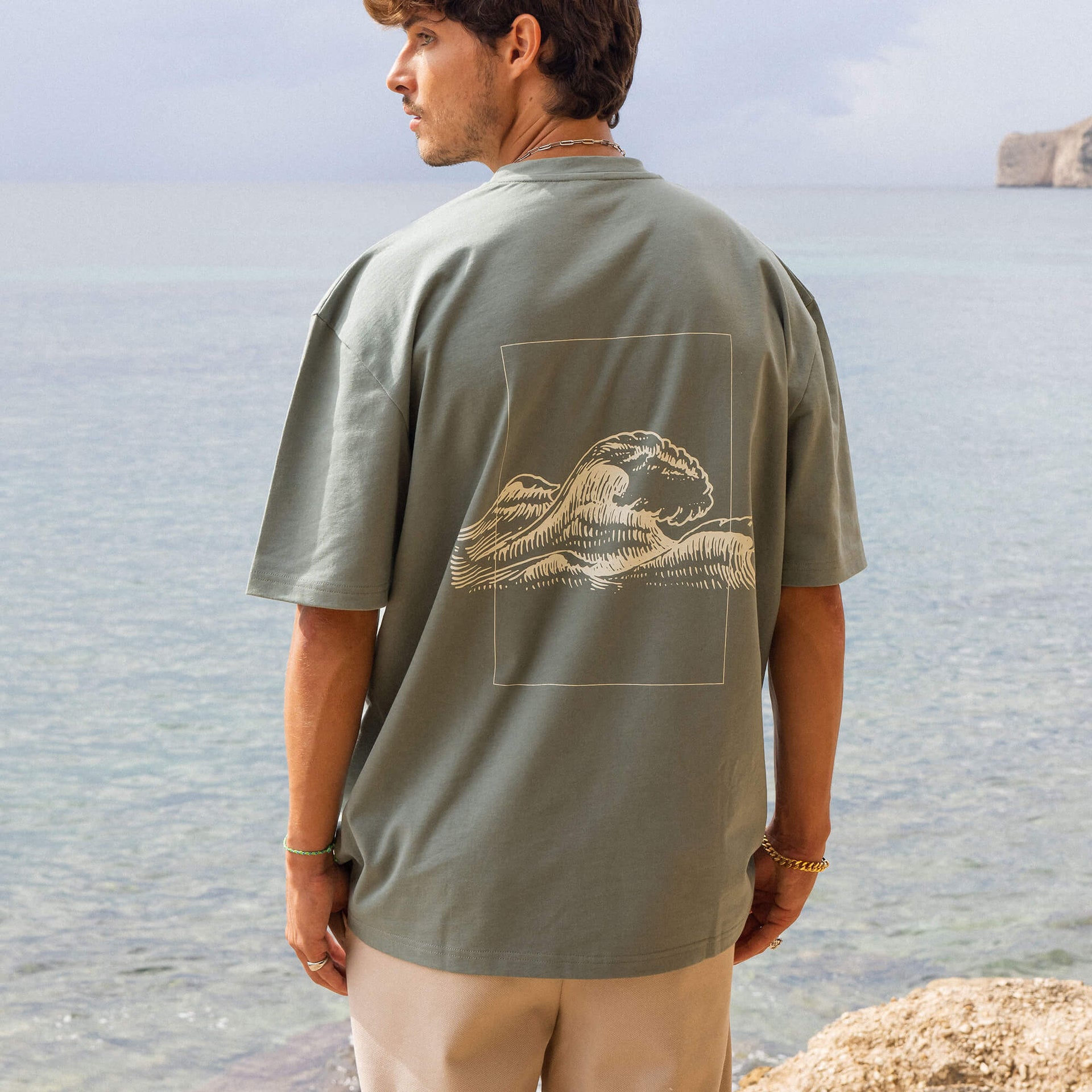 Graues T-Shirt mit Wellenmotiv von PURELEI, lässig am Strand getragen.