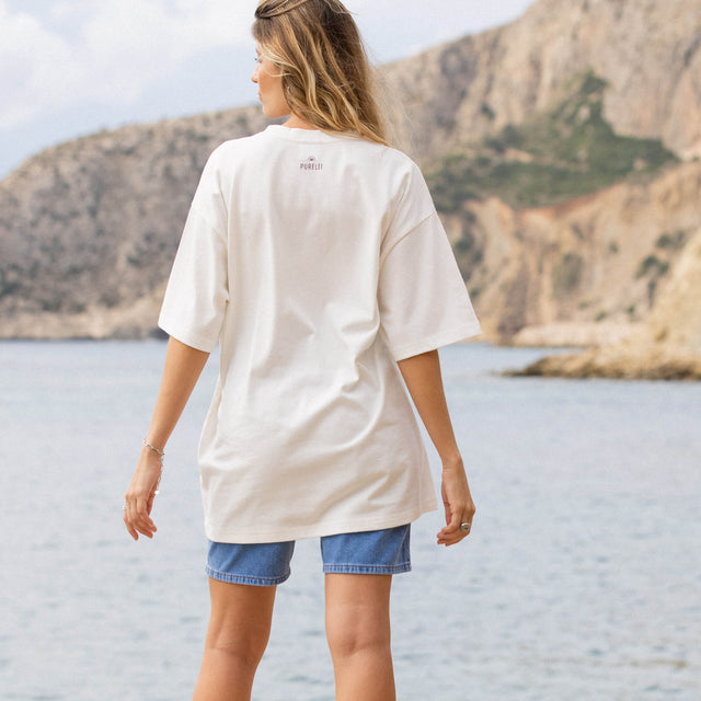 Weißes, lässiges T-Shirt von PURELEI, getragen am Strand mit natürlichem Hintergrund.